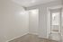 Modern apartment hallway with warm gray tones, soft carpet, and illuminated doorway leading to a cozy bathroom.