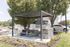 Charming outdoor space at ReNew Howard Crossing with a modern pergola, picnic table, and stylish stone grill, surrounded by lush greenery.