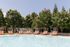 Inviting poolside retreat at ReNew Howard Crossing with stylish loungers under clear blue skies, surrounded by lush greenery.