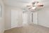 Inviting bedroom with plush carpeting, ceiling fan, and soft natural light, offering a serene and cozy atmosphere.
