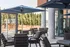 Chic outdoor patio with modern seating and large umbrellas, overlooking lush greenery for a luxurious and relaxing atmosphere.