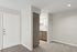 Welcoming apartment entryway with plush carpeting and a peek into the modern kitchen, featuring sleek cabinetry and a bright, airy design.