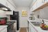 Modern kitchen with sleek white cabinets, granite countertops, black appliances, and a touch of vibrant decor, perfect for culinary enthusiasts.