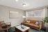 Bright and inviting living room with a modern leather sofa, sleek wooden chair, stylish decor, and abundant natural light.