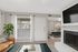 Charming living room with a cozy leather sofa, elegant fireplace, and large window inviting natural light. Adjacent dining area with stylish decor enhances the open, airy ambiance.