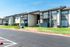 Charming apartment complex with modern balconies, well-maintained landscaping, and ample parking in a sunlit neighborhood.