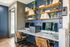 Elegant home office space with dual workstations, chic floating shelves adorned with books and plants, and a stylish navy blue accent wall.