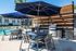 Inviting outdoor patio with sleek seating, large umbrellas, and modern grills beside a sparkling pool, perfect for entertaining and relaxation.