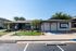 Inviting leasing office exterior with modern architecture, vibrant greenery, and convenient parking.