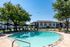 Inviting outdoor pool with sunlit lounge area and lush green surroundings in a modern apartment community.