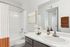 Modern bathroom with elegant design, featuring a sleek white vanity, chrome fixtures, and tasteful decorative accents.