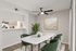 Elegant dining area with a sleek marble table, modern green chairs, and a view into a stylish kitchen, perfect for entertaining.