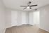 Bright, spacious room with modern light wood flooring, featuring fresh neutral walls and a ceiling fan for comfort.