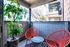Charming patio with vibrant red chairs, accentuated by lush greenery and natural light, offering a cozy outdoor escape.