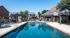 Inviting outdoor pool area with comfortable lounge chairs and shaded seating, perfect for relaxation and enjoyment under the bright blue sky.