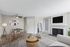 Modern living room with cozy fireplace, elegant wall art, stylish round dining table, and contemporary decor.