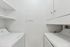 Bright and efficient laundry room with modern washer and dryer, featuring ample storage shelves and sleek cabinetry.
