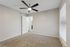 Spacious bedroom with plush carpet, modern ceiling fan, and ample natural light streaming through large windows.