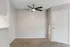 Chic apartment entryway showcasing modern ceiling fan, textured carpet, and natural light from a window with blinds.