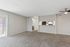 Bright and spacious living area with plush carpet, ceiling fan, and large window. Open kitchen with a modern design adds to the inviting atmosphere.