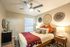 Inviting bedroom with modern decor, featuring a cozy bed with vibrant pillows, artistic wall hangings, and elegant side tables with lamps.