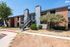 Charming red-brick apartment complex with modern stairway access, surrounded by lush greenery and clear blue skies.