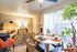 Bright and welcoming living-dining area with modern decor, stylish furniture, and abundant natural light from large windows.