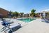 Inviting outdoor swimming pool with stylish lounge chairs and umbrellas, surrounded by modern residential apartments and lush greenery.