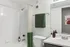 Modern bathroom featuring a sleek white and green color scheme with a bathtub, stylish shower curtain, and elegant vanity.