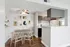 Charming apartment dining area with modern decor, cozy wooden chairs, and an open kitchen layout featuring stylish cabinetry.