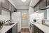 Cozy kitchen with sleek white countertops, dark cabinetry, and modern appliances, accented by a citrus-themed art piece.