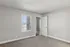 Bright and airy empty room with plush carpet and open door, inviting natural light through large window blinds.