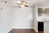 Charming apartment interior with a modern ceiling fan, sleek wooden flooring, and elegant gray cabinetry, perfect for a cozy dining nook or workspace.