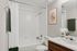 Elegant bathroom featuring a pristine white bathtub, granite countertop, and chic modern decor.