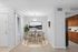 Modern dining area with chic wooden furniture, elegant wall art, and adjacent to a stylish kitchen with dark wood cabinets.