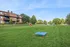 Inviting apartment complex with lush green playground and modern play equipment, perfect for families.