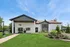 Charming residential building with a modern entrance, surrounded by lush landscaping and vibrant greenery under a clear blue sky.