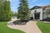 Charming apartment entrance surrounded by lush greenery, leading to a tranquil pool area under a clear blue sky.