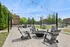 Charming outdoor patio area with modern seating, cozy fire pit, and decorative string lights, perfect for relaxation and gatherings.