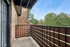 Charming apartment balcony with wood railing, offering serene views of lush greenery for a peaceful retreat.
