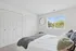 Bright and airy bedroom with plush bedding, ample closet space, and a large window showcasing a serene outdoor view.