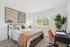 Bright and cozy bedroom featuring a stylish bed with elegant pillows, modern artwork, and a convenient desk by the window, perfect for serene living.