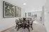 Elegant dining area with a stylish round table and four chairs, complemented by large nature-themed artwork, in a bright open-plan kitchen setting.