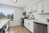 Bright and modern kitchen with sleek stainless steel appliances, white cabinetry, and elegant wood flooring accented by natural light from large windows.