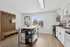 Bright and airy kitchen with modern white cabinetry, stainless steel appliances, and a central island, accented by a window view of lush greenery.