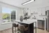 Bright and modern kitchen with sleek white cabinets, stainless steel appliances, and a stylish breakfast bar with plush seating and decorative vase.