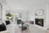 Bright and inviting living room featuring a cozy fireplace, elegant white sofa, and modern decor with abundant natural light.