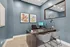 Modern office space with stylish blue walls, elegant desk setup, and contemporary decor showcasing vibrant framed art.