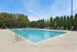 Inviting outdoor swimming pool with elegant lounge chairs and lush greenery, perfect for relaxation and enjoyment on a sunny day.