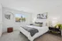Bright and cozy bedroom featuring a plush bed with stylish decor, a large window with a serene view, and modern furnishings.